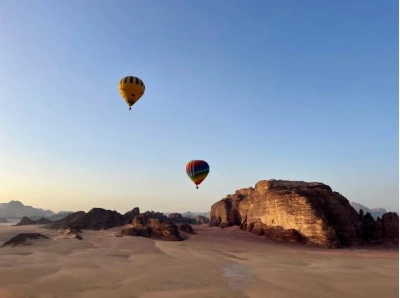 Hot air balloon floating over Wadi Rum desert at sunrise
